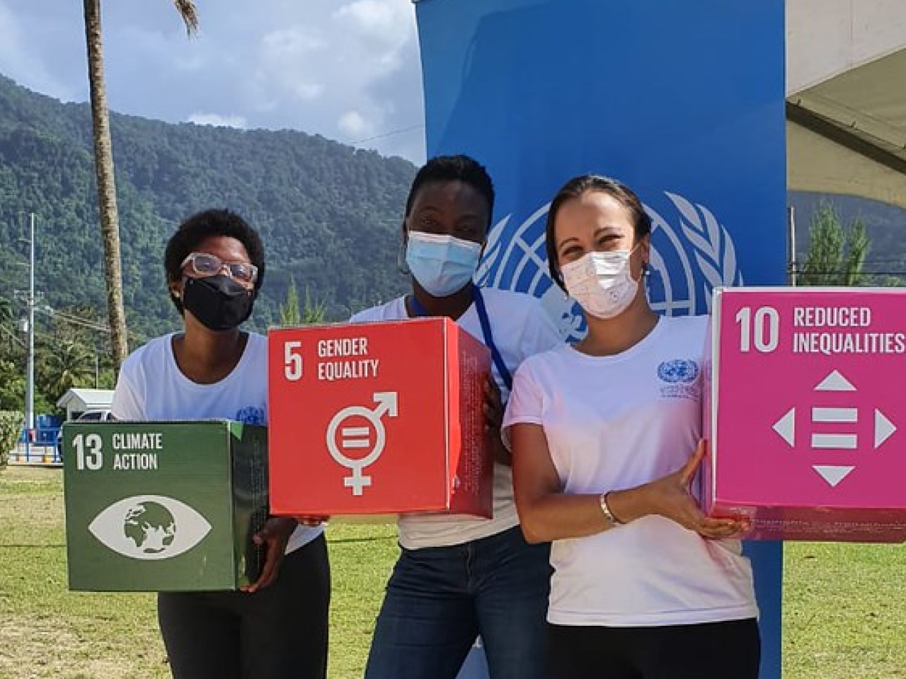 Three women hold cubes with different SDGs written on them