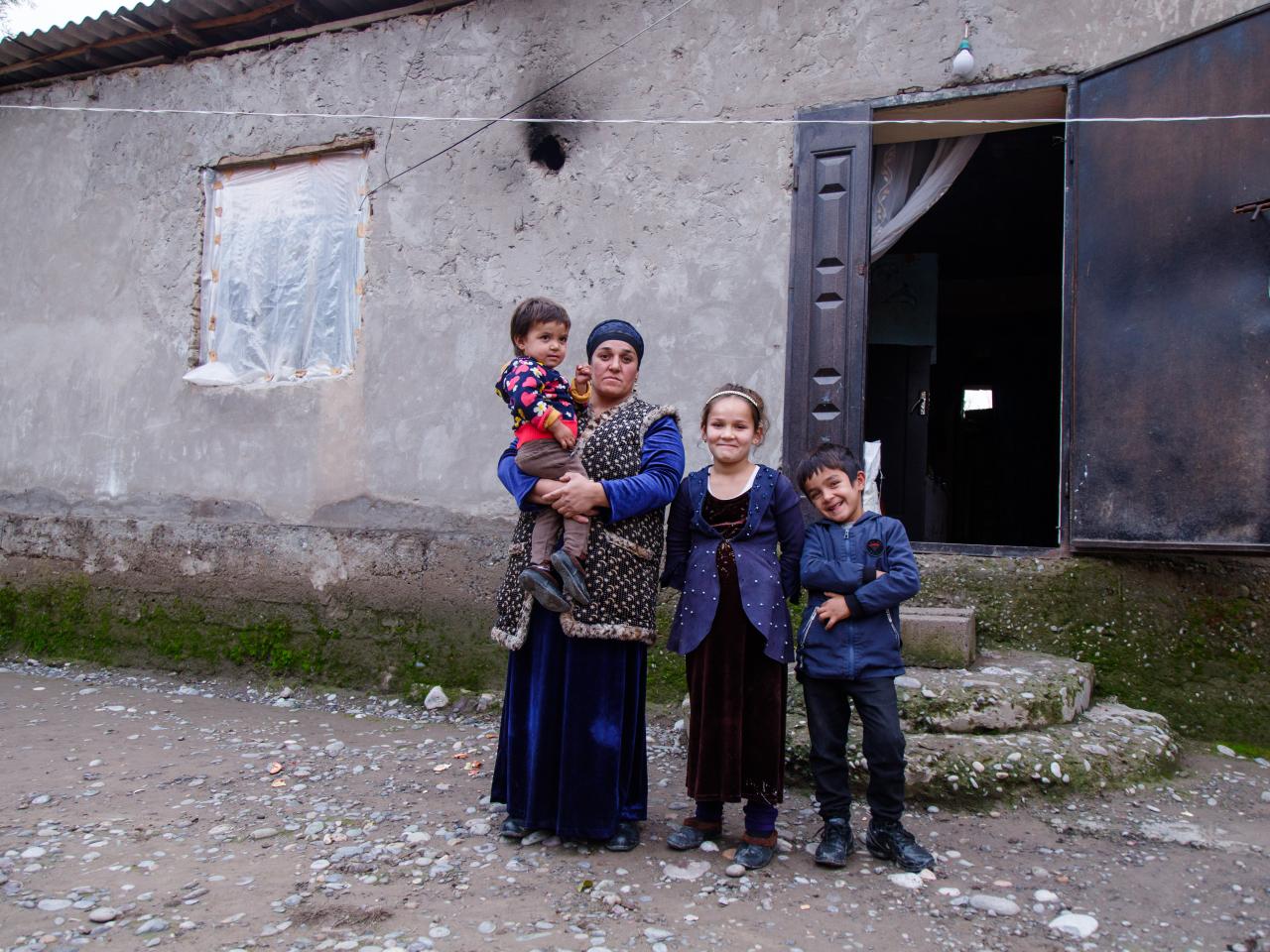 A woman and three children in front of home