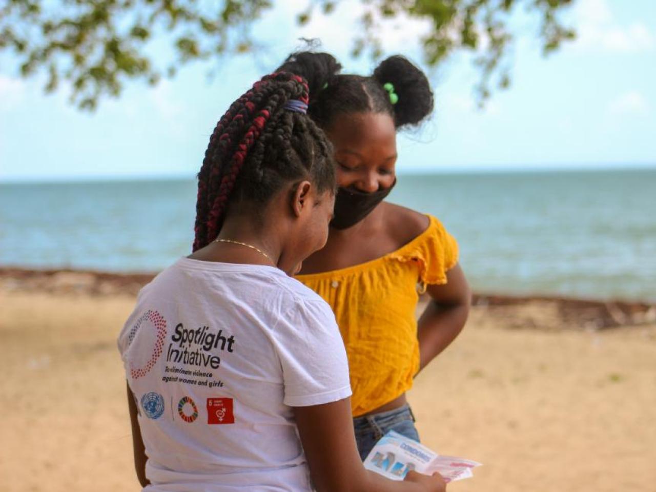 Two girls smiling on a beach, one wearing Spotlight t-shirt