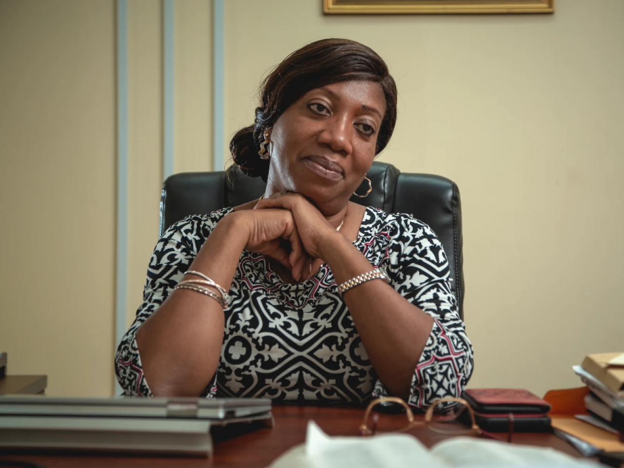 A woman in a black and white patterned shirt sitting behind a desk