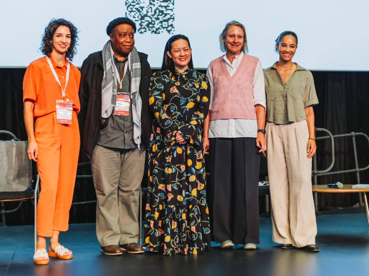 Four women and one man standing on a stage smiling