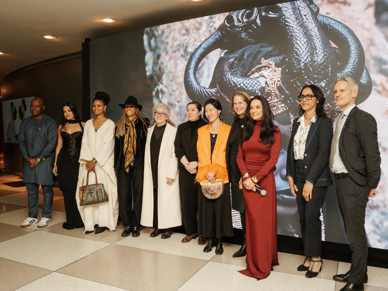 Women and men standing in front of large artwork