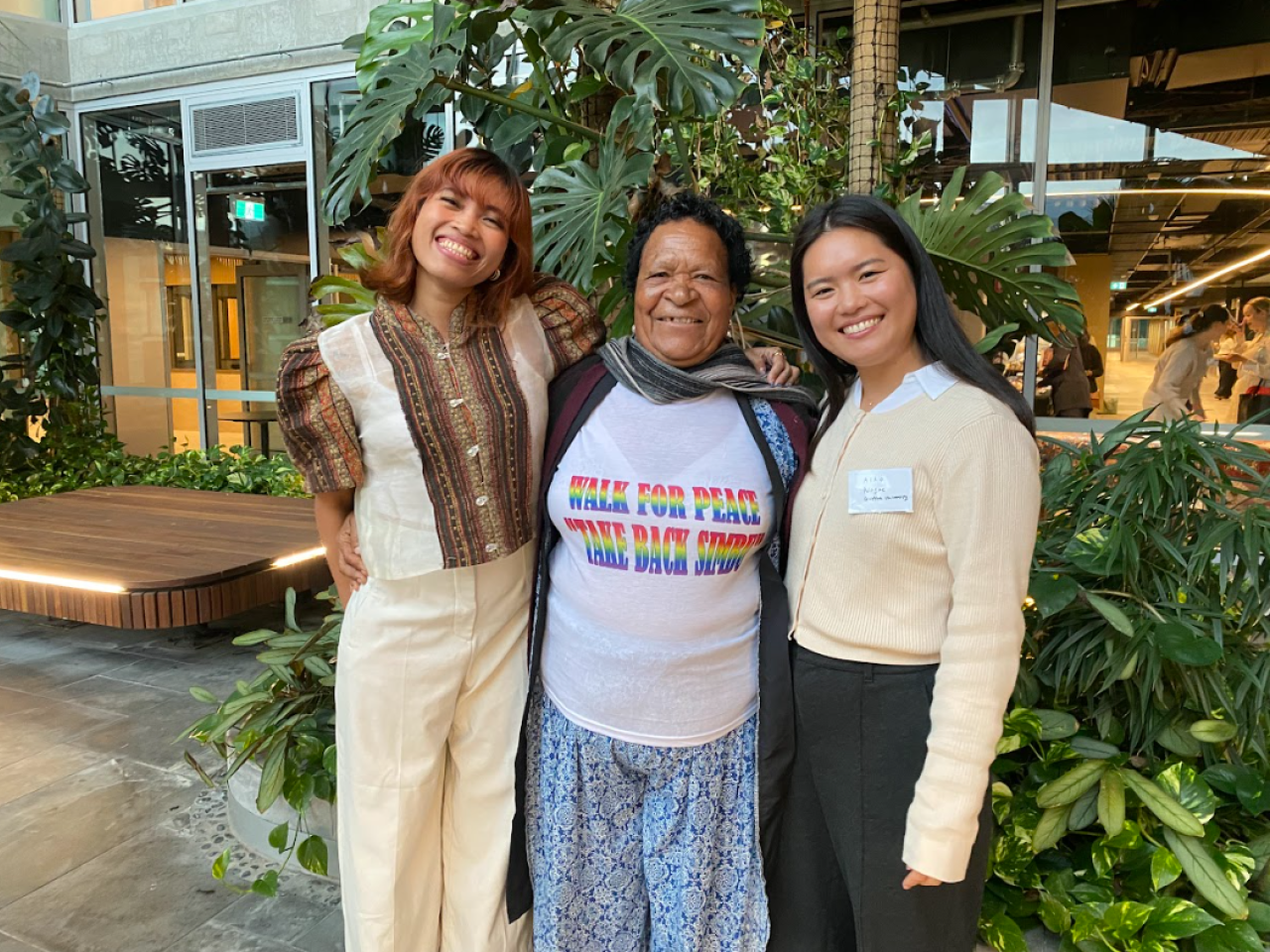Three women stand outside with arms around each other