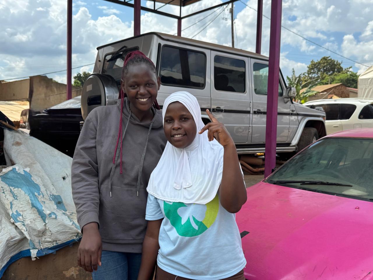 Two girls smiling in front of cars