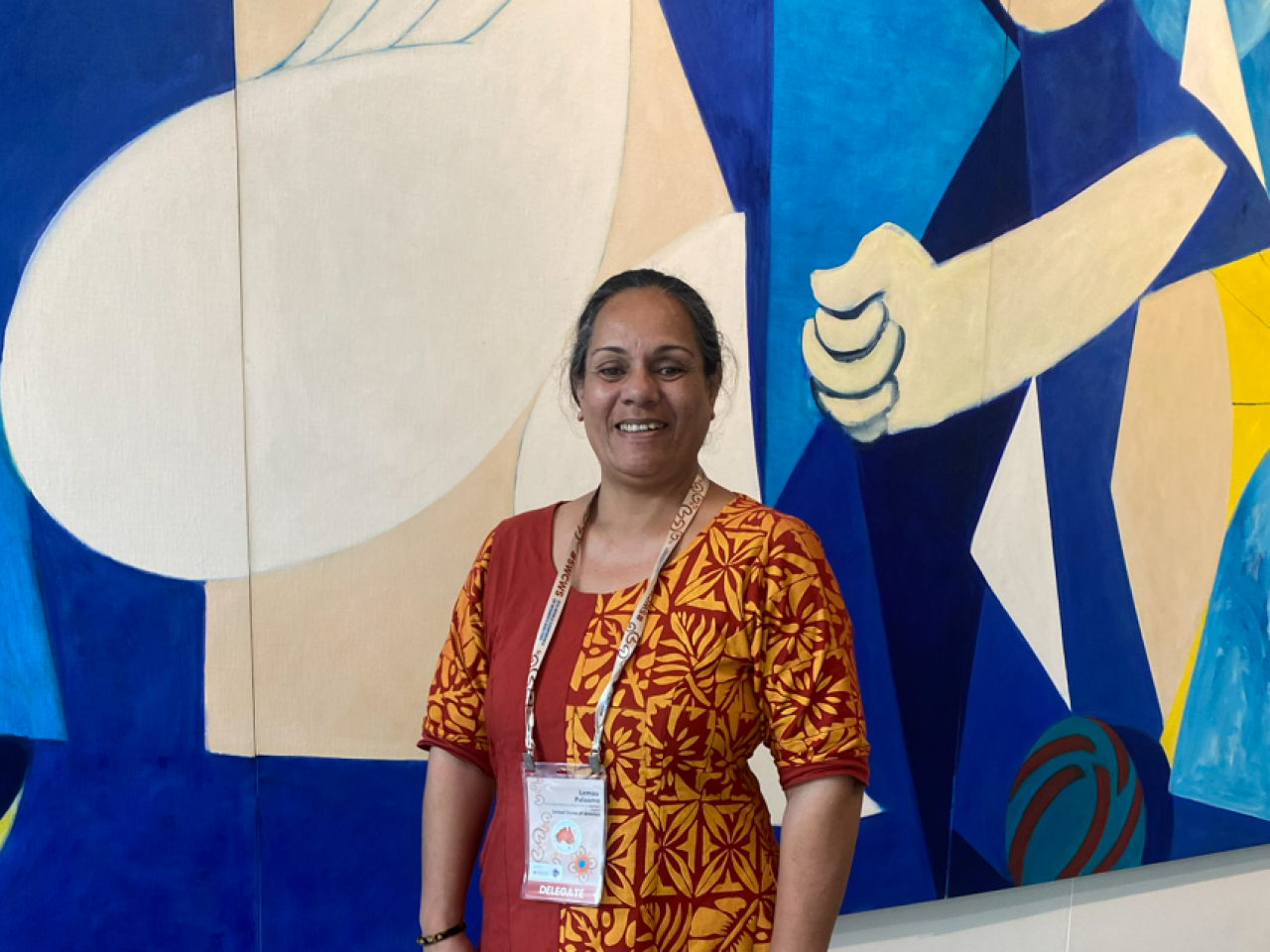 Lemau smiling in front of an abstract painting