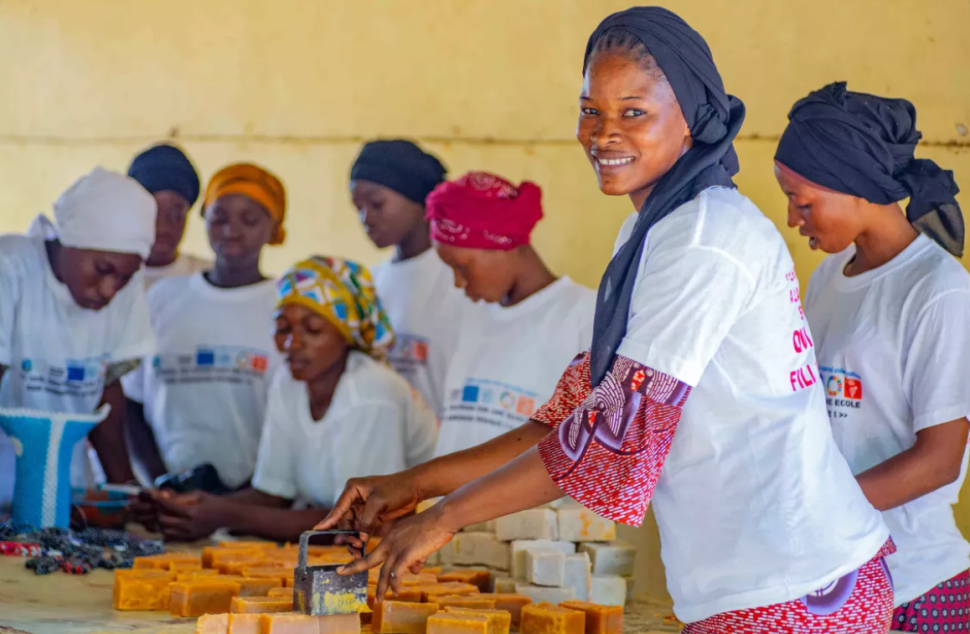 Aminata making soap with other women and girls