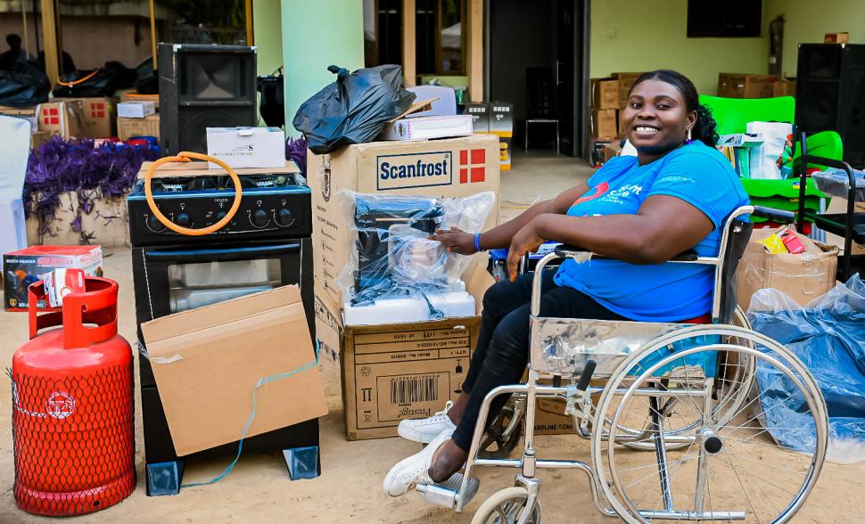 Smiling woman in wheelchair posing in front of supplies