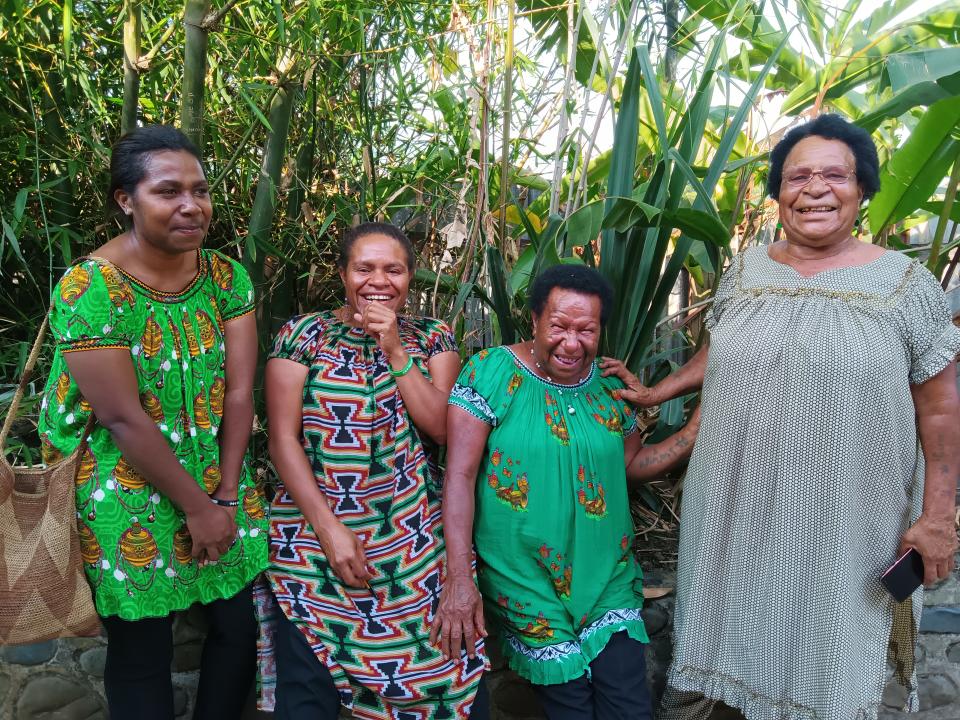 Four laughing women standing in front of trees