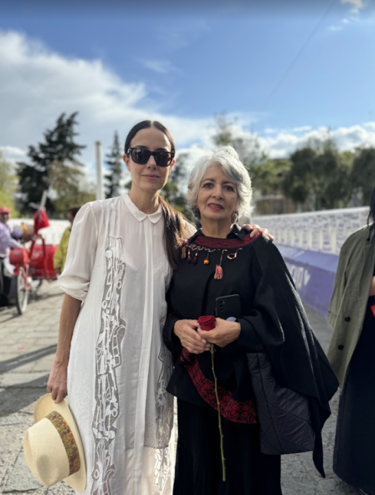 Two women with arms around each other smile at camera