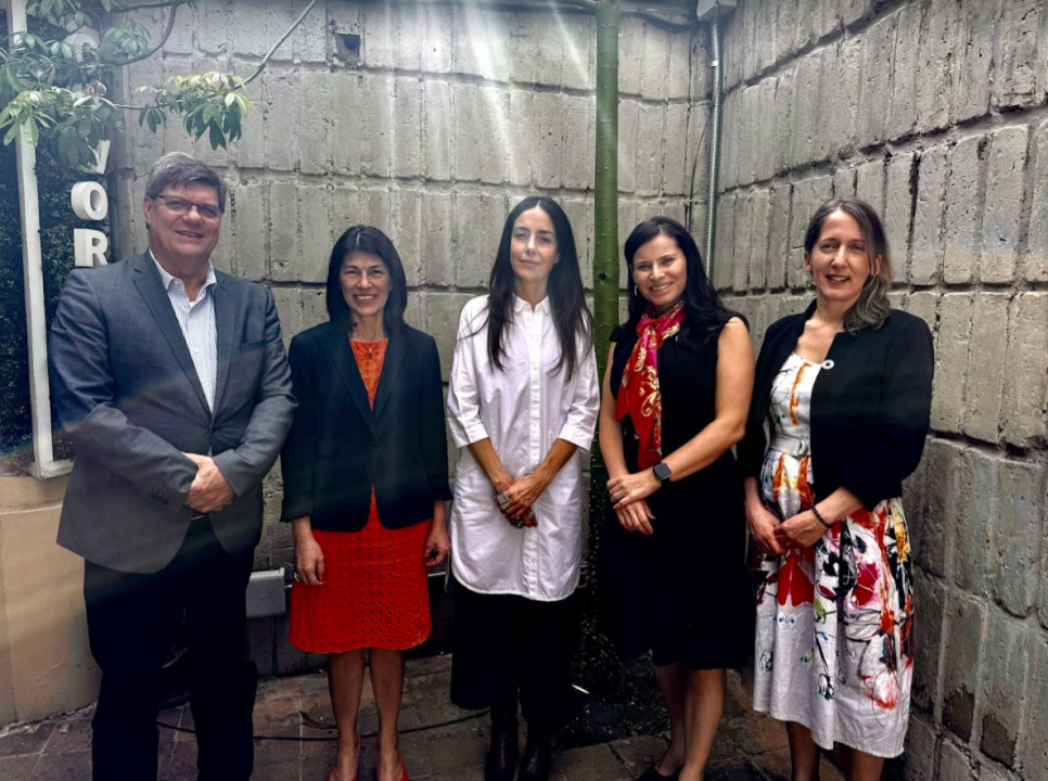 One man and four women stand outside and smile at camera