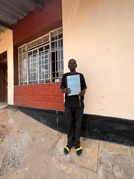 Man holding document stands in front of building