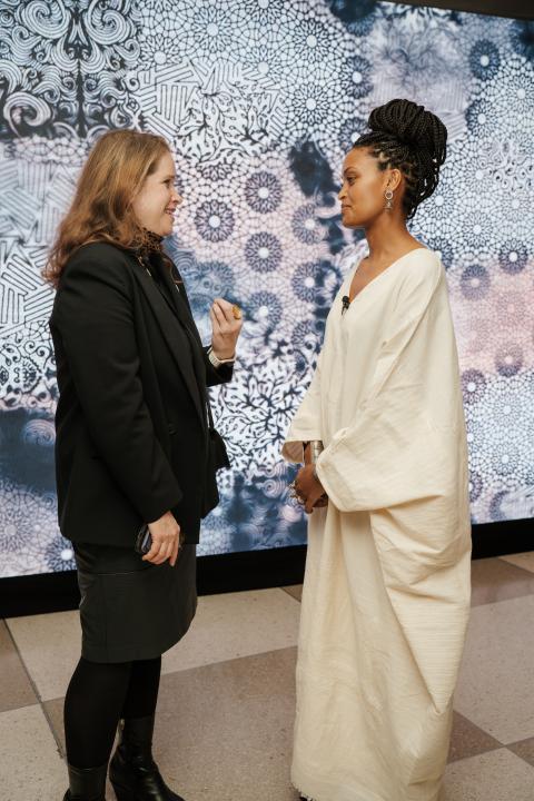 Two women talking in front of art