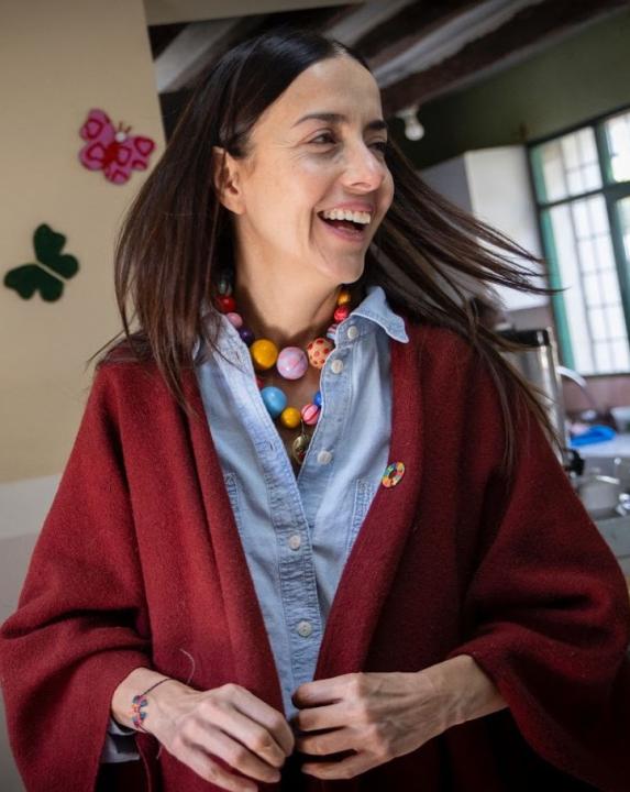 Ms Suarez smiling in a red cardigan