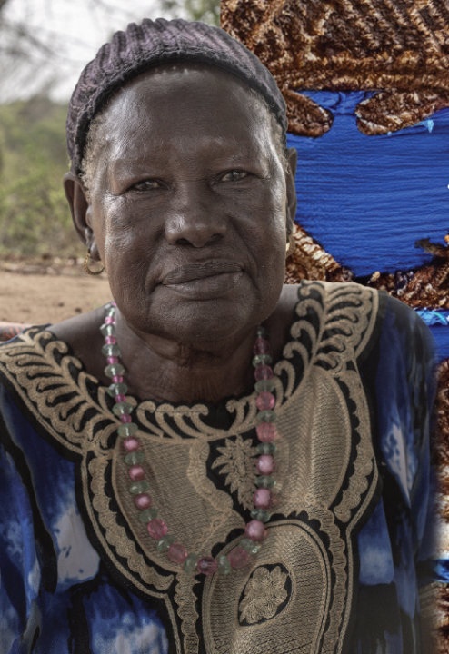 A woman in a blue and gold dress looks into the camera