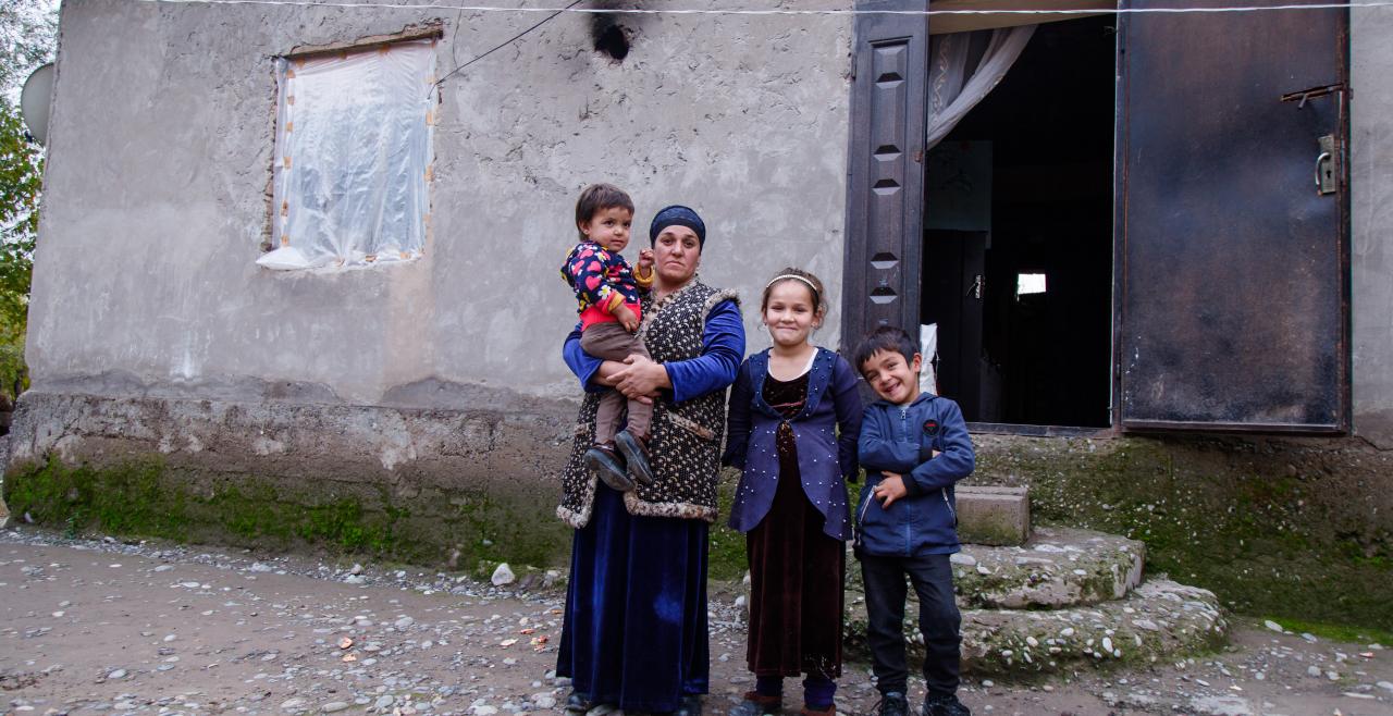 A woman and three children in front of home