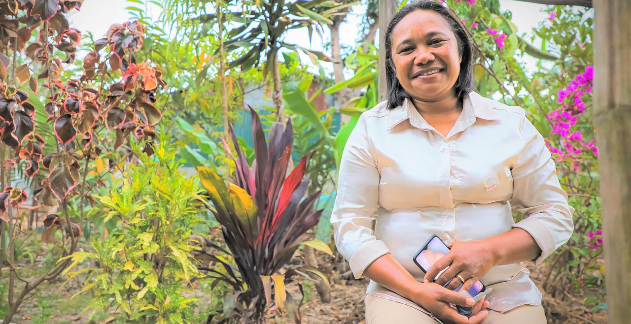 A smiling woman stands in front of garden