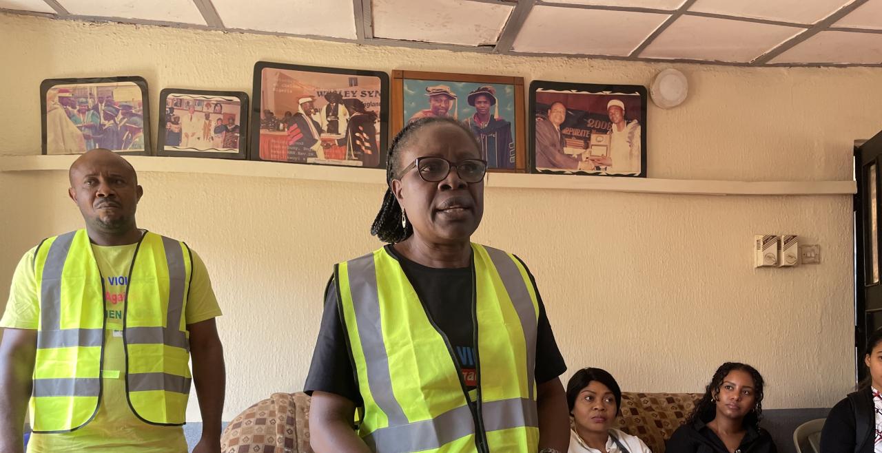 A woman and man in high viz vests stand in from of a crowd