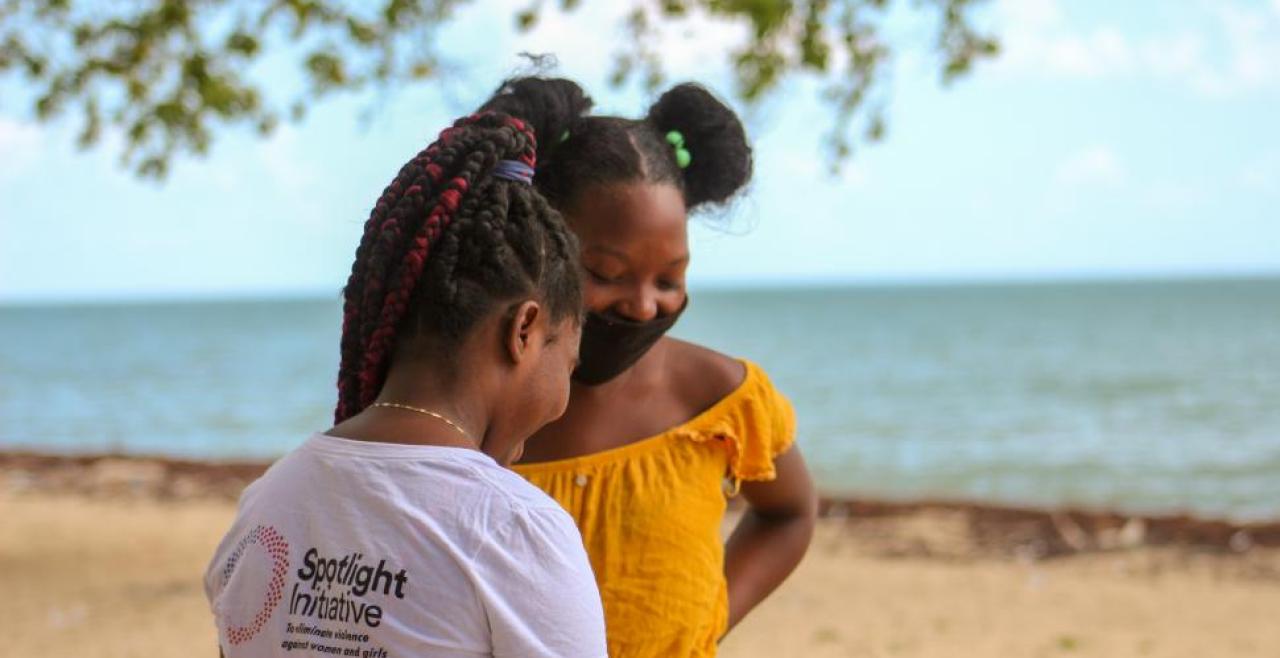 Two girls smiling on a beach, one wearing Spotlight t-shirt