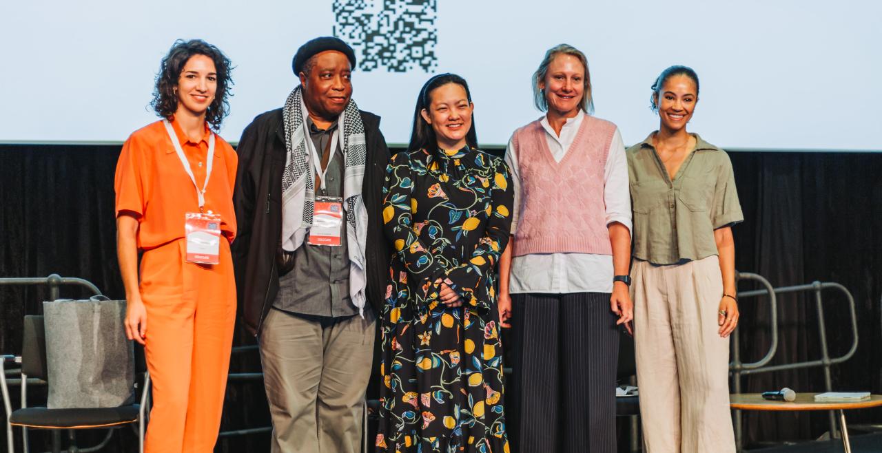 Four women and one man standing on a stage smiling