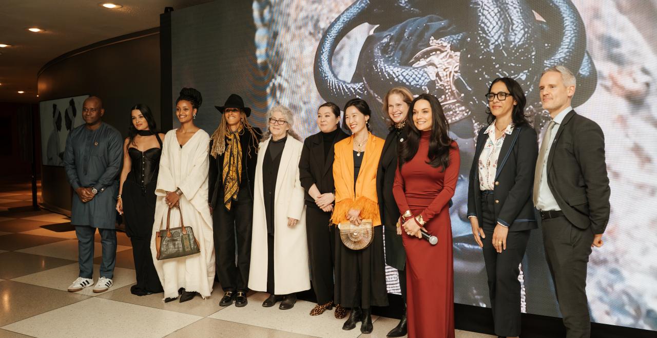 Women and men standing in front of large artwork