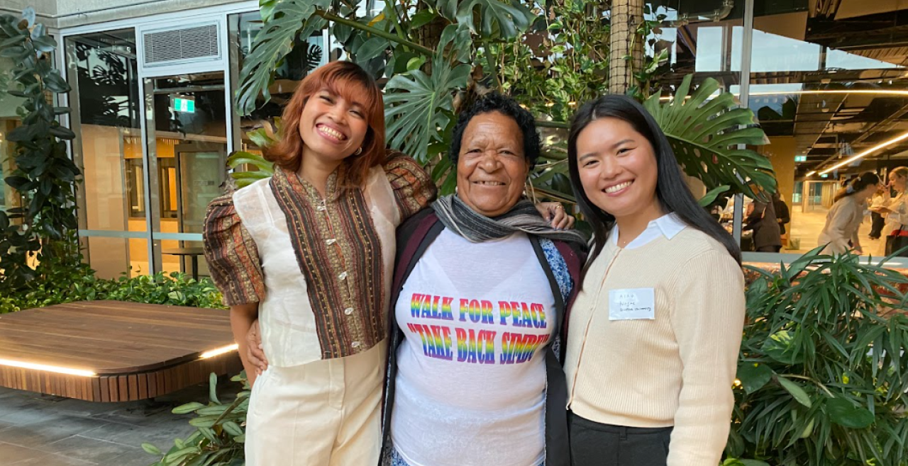 Three women stand outside with arms around each other