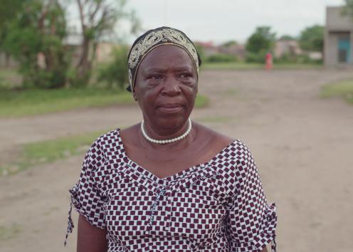 A woman in a patterned dress walks down a rural road
